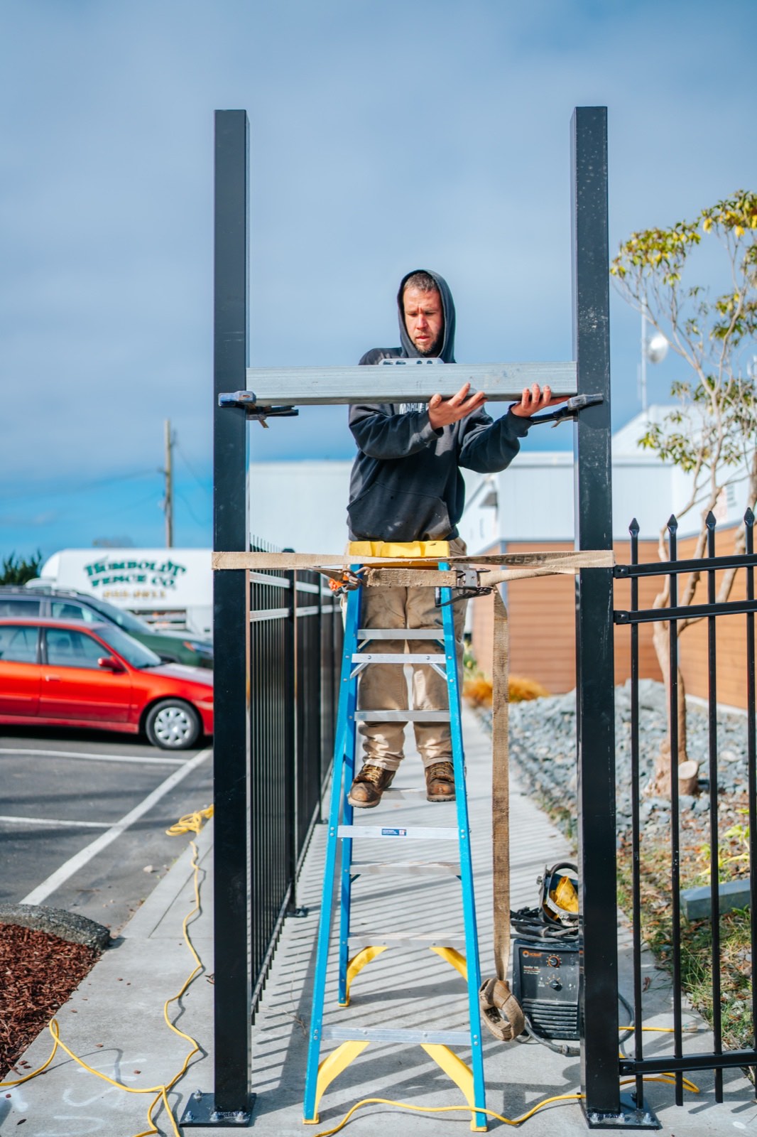 Crew installing ornamental iron commercial fence top rail with branded Humboldt Fence Co. truck on site