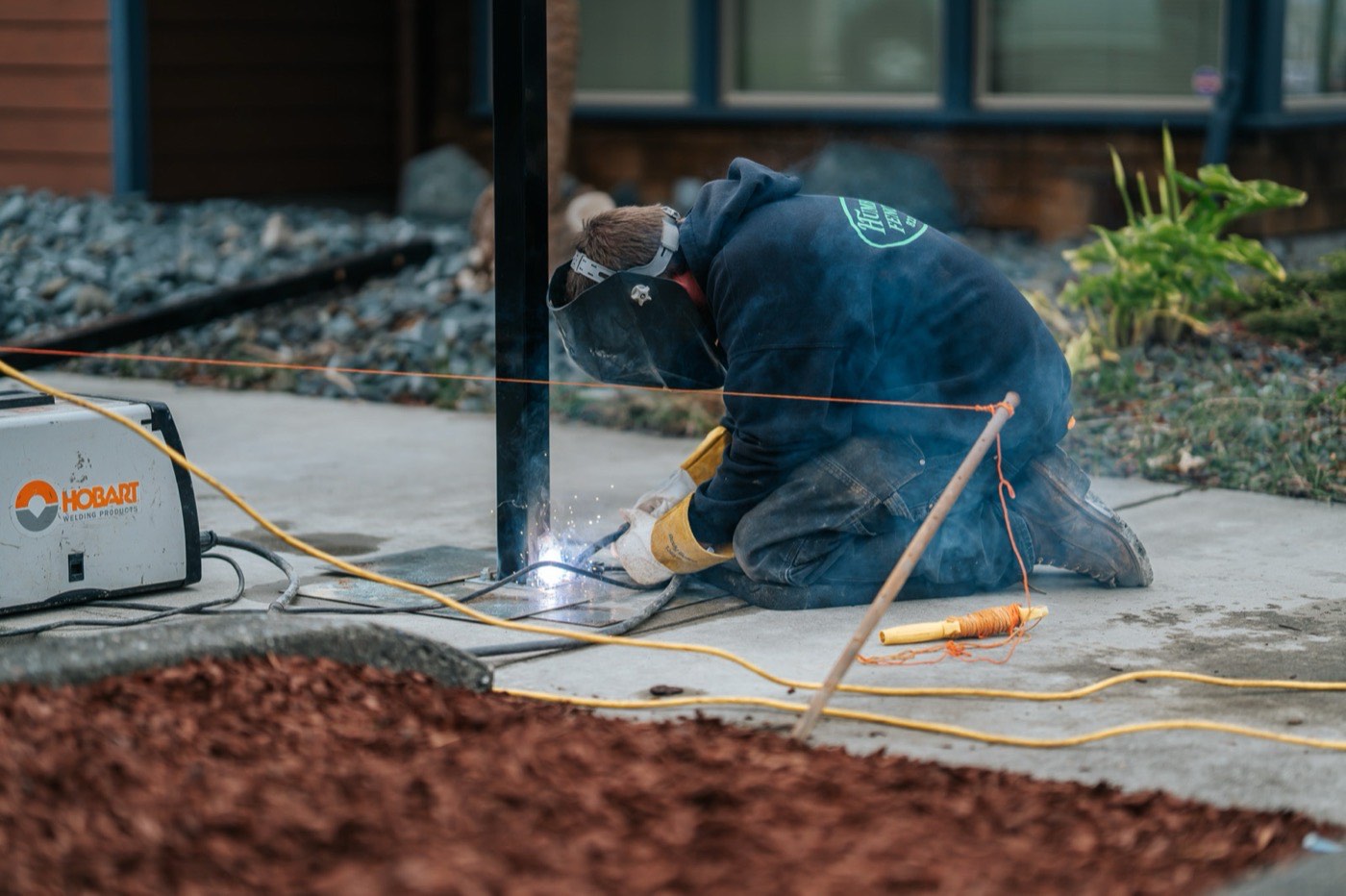 Humboldt Fence installer welding the base of a commercial ornamental iron post, sparks visible