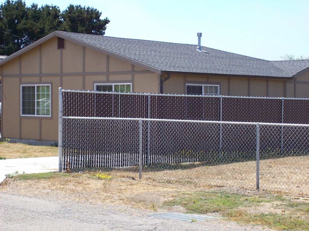 Chain link fence with pre-woven privacy slats